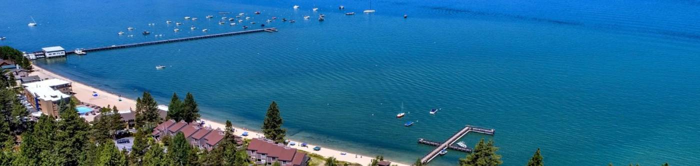 Lakeland Village houses surrounded by trees along the South Lake Tahoe coast on a sunny day,